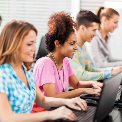 Grupo de jóvenes de diferentes orígenes trabajando felizmente con ordenadores portátiles en la oficina moderna de Rating Leader, sonriendo y colaborando, con un ambiente de trabajo placentero